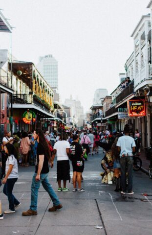 Bustling scene on Bourbon Street, New Orleans with a lively crowd enjoying an evening stroll.